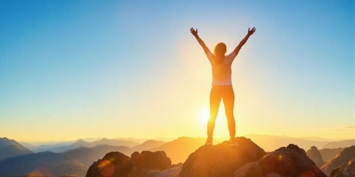 Person celebrating confidence on mountain peak at sunrise.